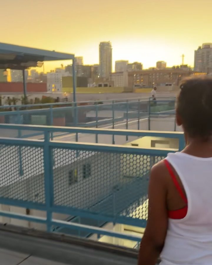 A resident on a rooftop terrace looking out at the downtown Los Angeles skyline at sunset